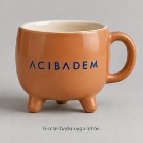 Oltu Üç Ayaklı Stoneware Kupa: Acıbadem logosunun dış yüzeyde temsili baskı uygulaması; üretilmiş numune veya gerçek müşteri siparişi fotoğrafı değildir.